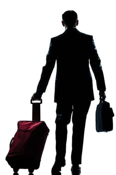 rear view one caucasian business traveler man walking with suitcase  full length silhouette in studio isolated white background