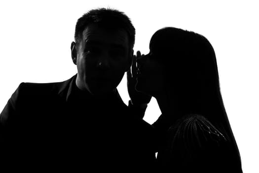 one caucasian couple man and woman  whispering at ear in studio silhouette isolated on white background