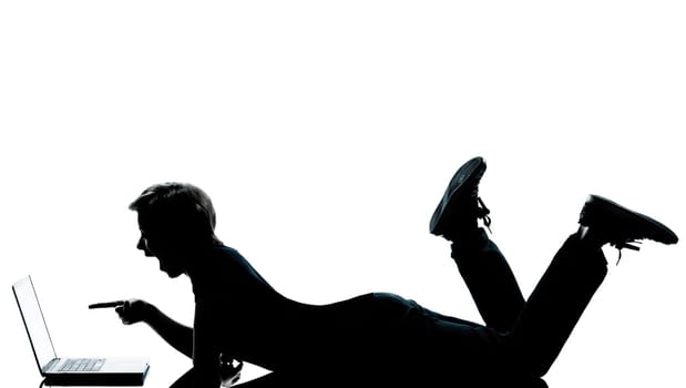 one caucasian young teenager silhouette boy girl computer computing laptop lying on front full length in studio cut out isolated on white background