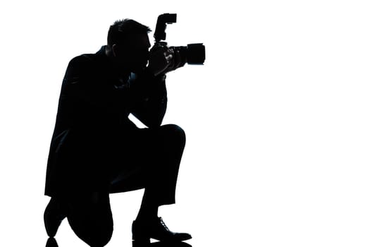 one caucasian man kneeling photographer full length silhouette in studio isolated on white background