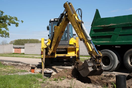 Excavator loading dumper truck tipper with sand on construction site