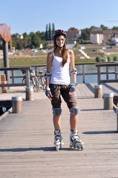 Woman standing around at a lake with inline skates