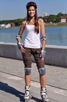 Pretty sportswoman stands on inline skater at a lake