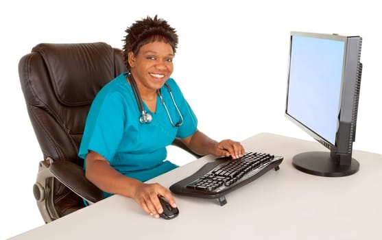 An African American nurse is smiling at the camera while sitting at her desk.
