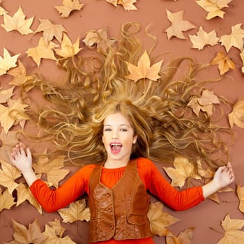 autumn fall little blond girl on dried tree leaves background and long spread hair