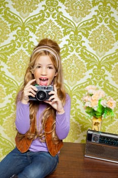 hip retro little girl shooting photo with vintage camera on wallpaper