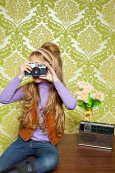 hip retro little girl shooting photo with vintage camera on wallpaper