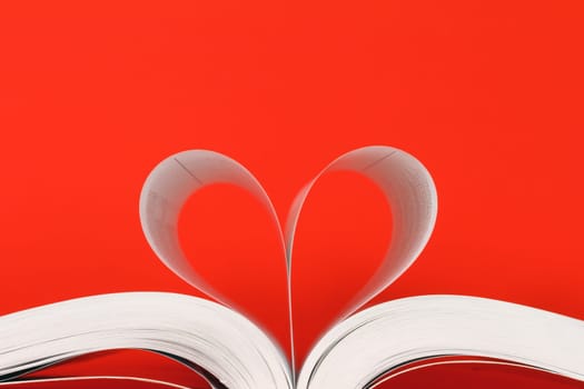 book with pages in heart shape over red background