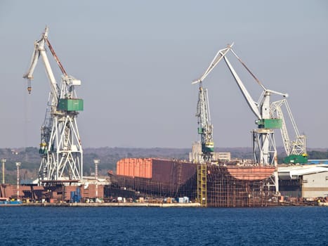 shipyard with docks and crane and blue sea