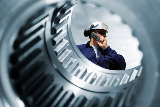 engineer, worker standing inside large gears and cogs machinery