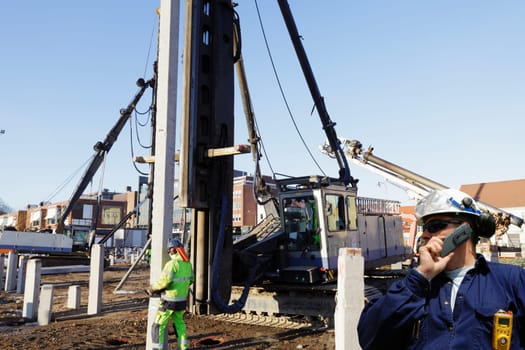 building workers inside construction-site, machinery in background