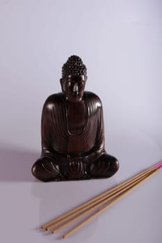 Wooden Buddha meditating with incense