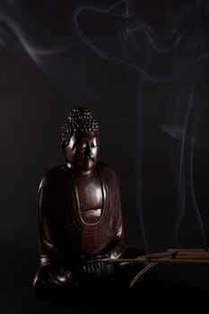 Wooden Buddha meditating on the black background