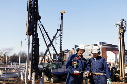 construction workers, engineers working inside building-site, machinery in background