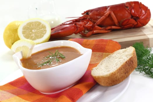 a bowl of lobster cream soup with dill and lemon