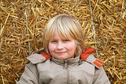 Boy sitting on straw bale