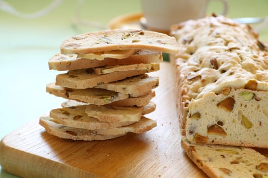 Fresh baked sweet pistachio bread sliced on a bread board with coffee.