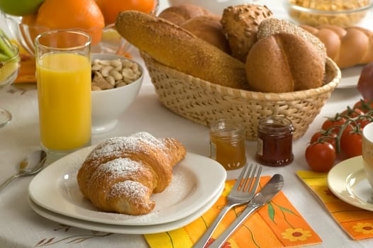 Croissant, juice, bread, fruits and coffee arranged for breakfast