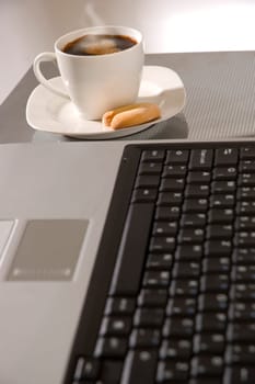 cup of hot coffee beside laptop close up