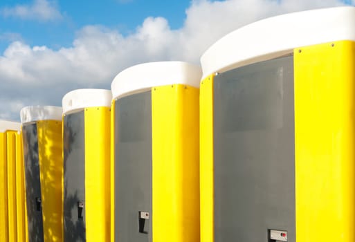 yellow portable toilets under a nice cloudy sky