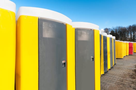 yellow portable toilets under a nice cloudy sky