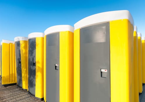 yellow portable toilets under a nice cloudy sky