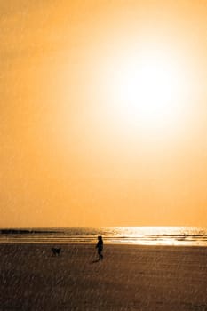 sunshine reflected on a golden beach during a rain storm with child and dog walking