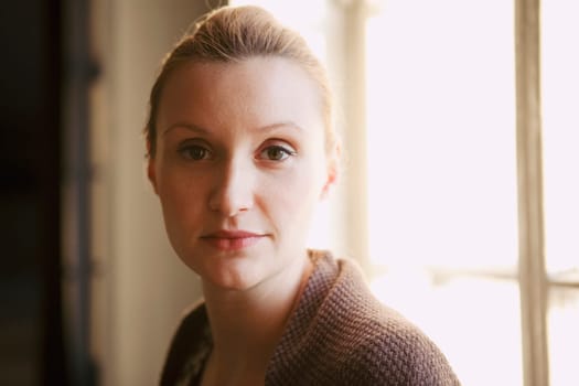 Portrait of a beautiful woman, looking serious. Natural portrait indoors.