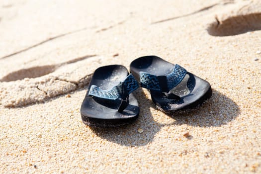 Close-up of flip flops in sand on the beach