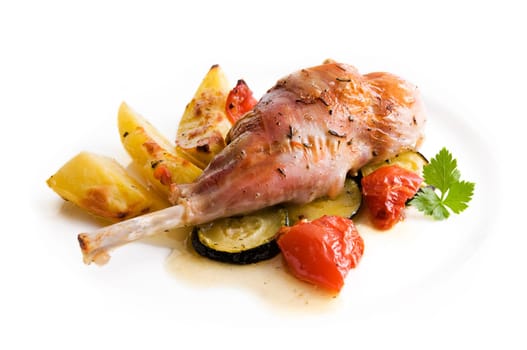 Roasted rabbit leg with potato and vegetables close up