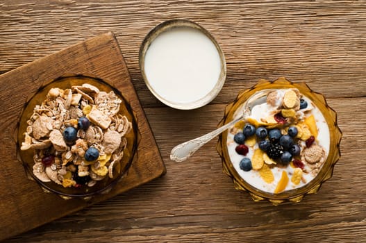 Fresh corn flakes with blueberries on wooden background