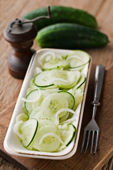 Fresh cucumber salad on wooden vintage background