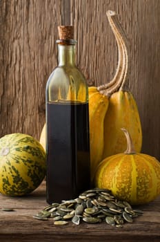 Fresh pumpkin oil on wooden background close up