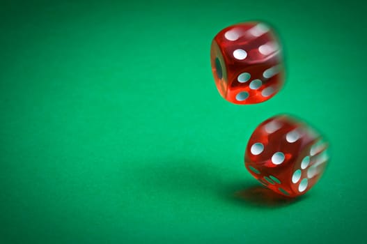 Red dices in midair on green background close up