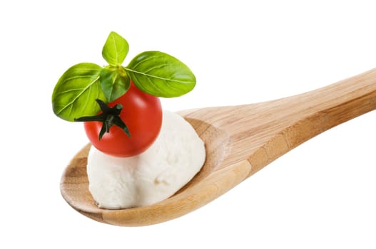 Tomato, mozzarella and basil on a wooden spoon close up