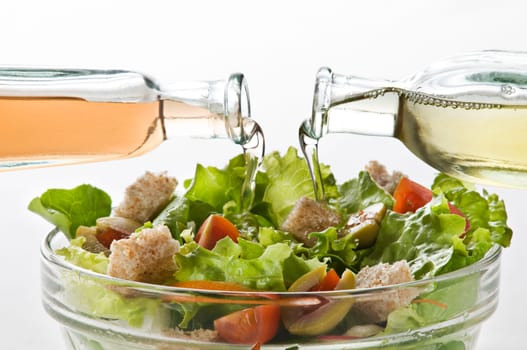 Olive oil and vinegar pouring in to green salad