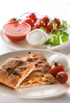 Freshly baked calzone with mozzarella, tomato and basil