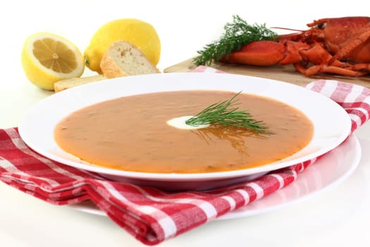 a bowl of lobster cream soup with dill and lemon