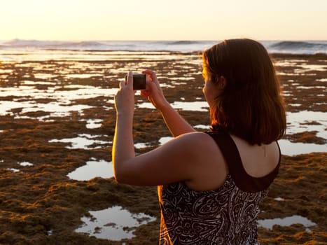 Photographer using smartphone to take a picture of setting sun