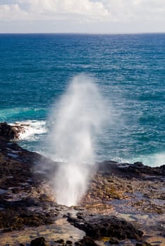 Vent of water from underneath lava rocks on coast of Kauai