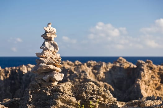 Pyramid shaped stack of rocks balanced on the edge of ocean