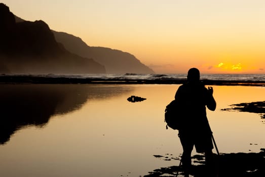 Silhoutted photographer of Na Pali coast by Ke&#039 e beach in Kauai at sunset