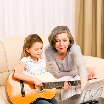 Young girl granddaughter sing play guitar to grandmother smile