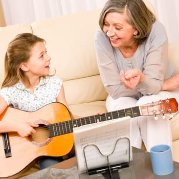 Young girl granddaughter sing play guitar to grandmother smile