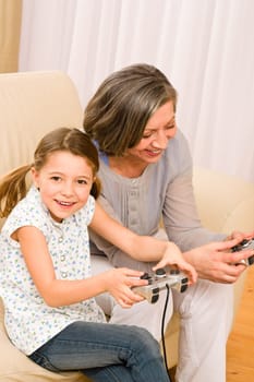Grandmother play computer game with enthusiastic young girl have fun smiling
