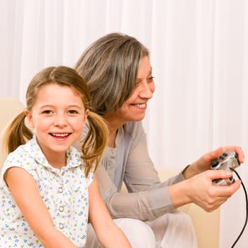 Grandmother play computer game with enthusiastic young girl have fun smiling