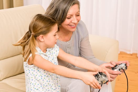 Grandmother play computer game with enthusiastic young girl have fun smiling