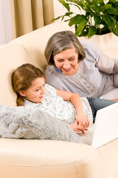 Grandmother with young girl use computer laptop happy together