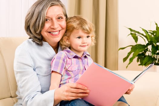 Grandmother and little girl reading book happy together at home