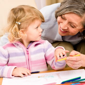 Grandmother and granddaughter drawing together with pencils at home